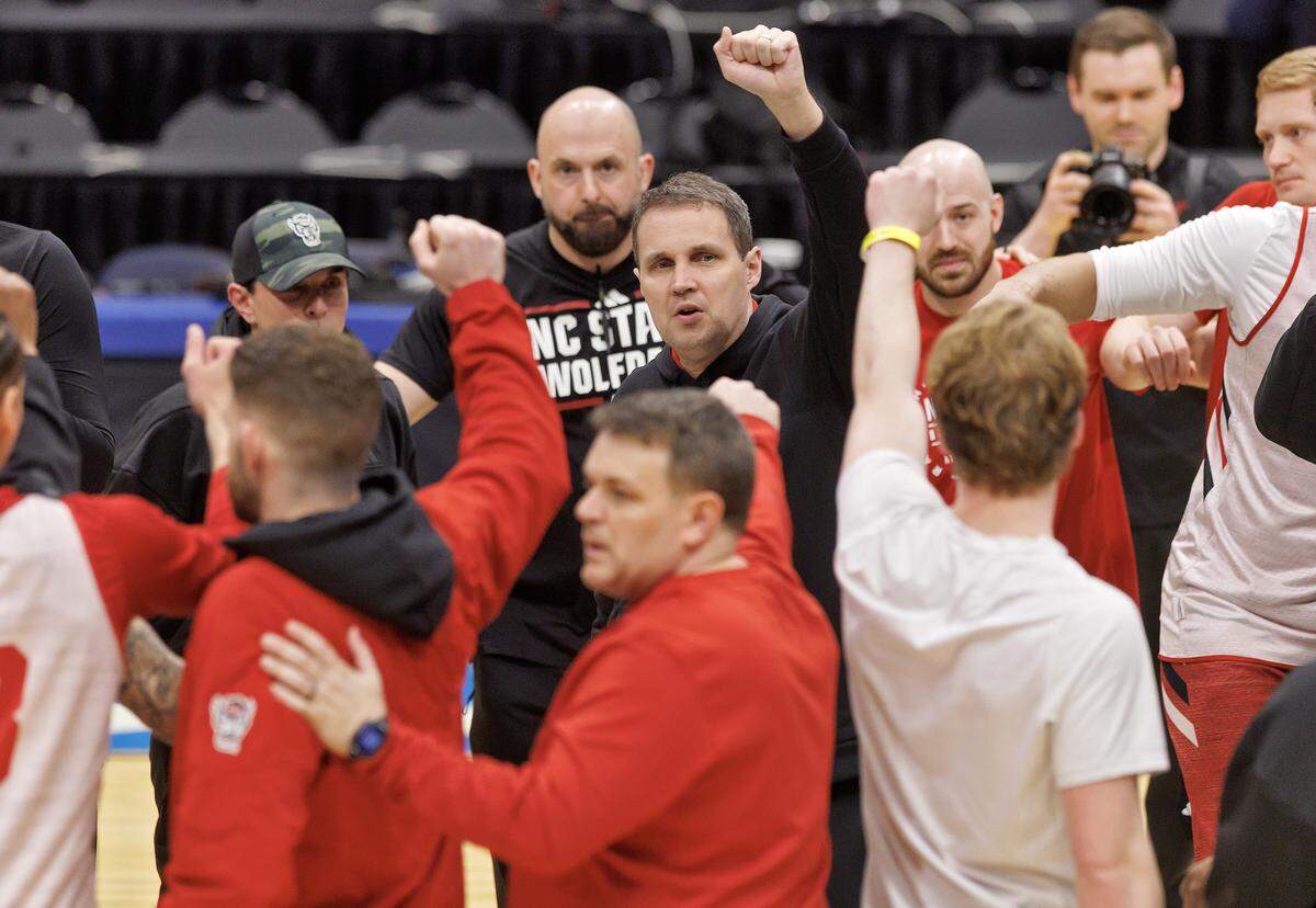 N.C. State head coach Will Wade, center, huddles with his team at the conclusion of practice at University of Dayton Arena in Dayton, Ohio on Monday, March 16, 2026. The Wolfpack will face Texas in the First Four on Tuesday.