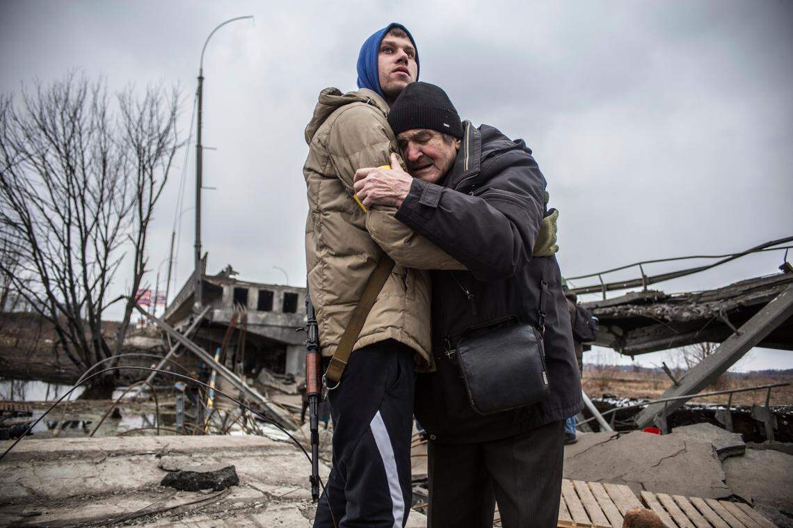 A Ukrainian Territorial Defence Forces member hugs a resident who leaves his home town following Russian artillery shelling in Irpin, on the outskirts of Kyiv, Ukraine, Wednesday, March 9, 2022. (AP Photo/Oleksandr Ratushniak)