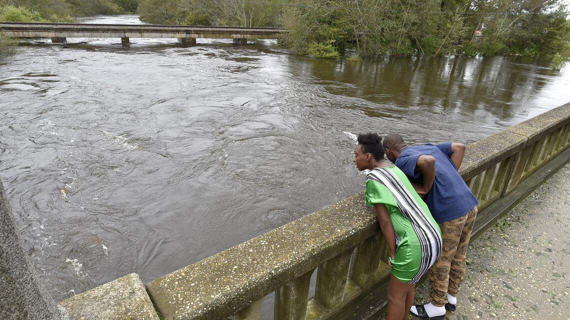 Taquana Sanders and George Green, of Fayetteville have a look at the rising waters of the Lumber River in Lumberton on Sept. 16, 2018. Heavy rains from Tropical Storm Florence are caused  widespread flooding in the area.