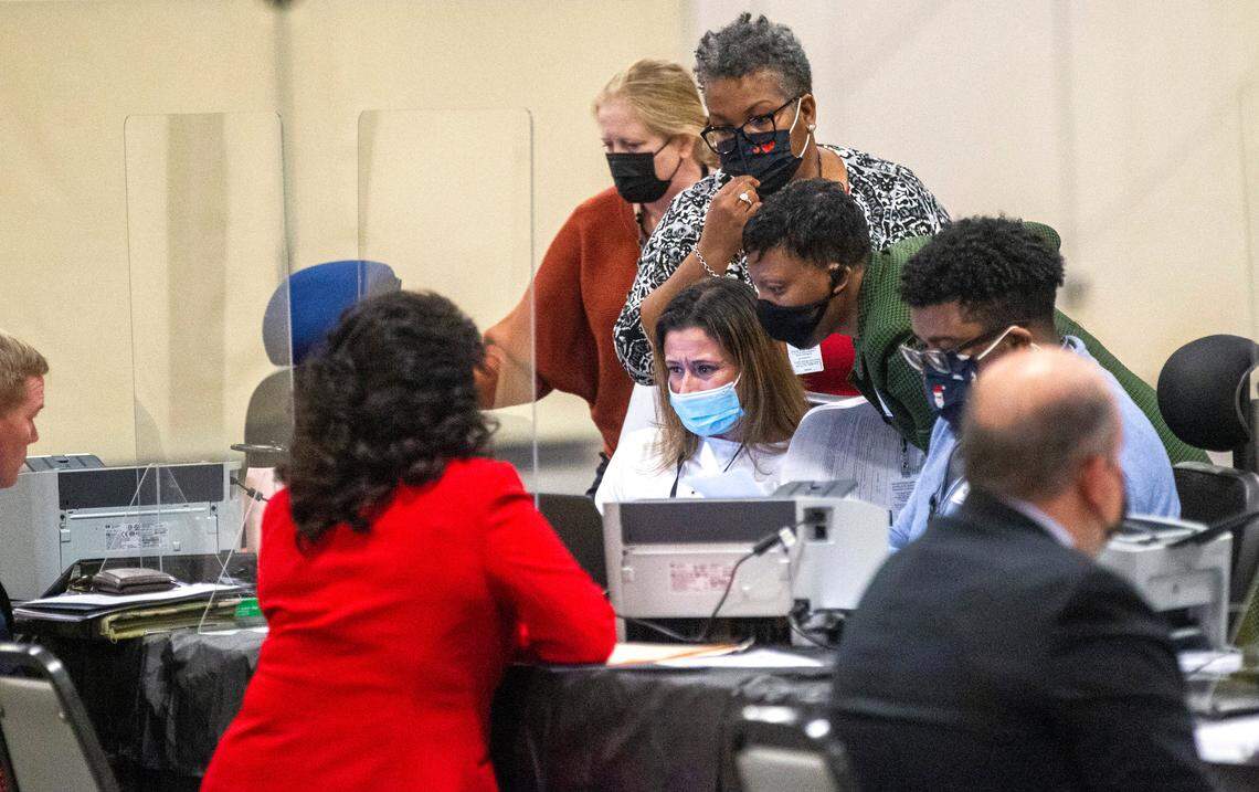 State Board of Elections workers huddle around a computer at the NC State Fairgrounds after a court order Monday temporarily blocked candidates from filing to run in some of the 2022 elections Monday, Dec. 6, 2021.