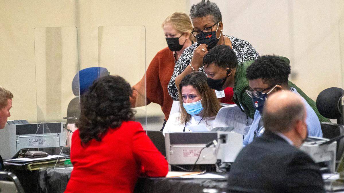 State Board of Elections workers huddle around a computer at the NC State Fairgrounds after a court order Monday temporarily blocked candidates from filing to run in some of the 2022 elections Monday, Dec. 6, 2021.