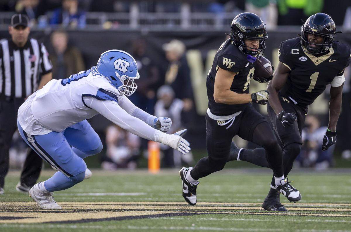 Wake Forest wide receiver Carlos Hernandez (8) breaks away from North Carolina’s defense lineman Smith Vilbert (8) after recovering a fumble by teammate Robby Ashford. Hernandez romped 51 yards for a touchdown to give Wake a 7-0 lead in the first quarter on Saturday, November 15, 2025 at Allegacy Stadium in Winston-Salem, N.C.