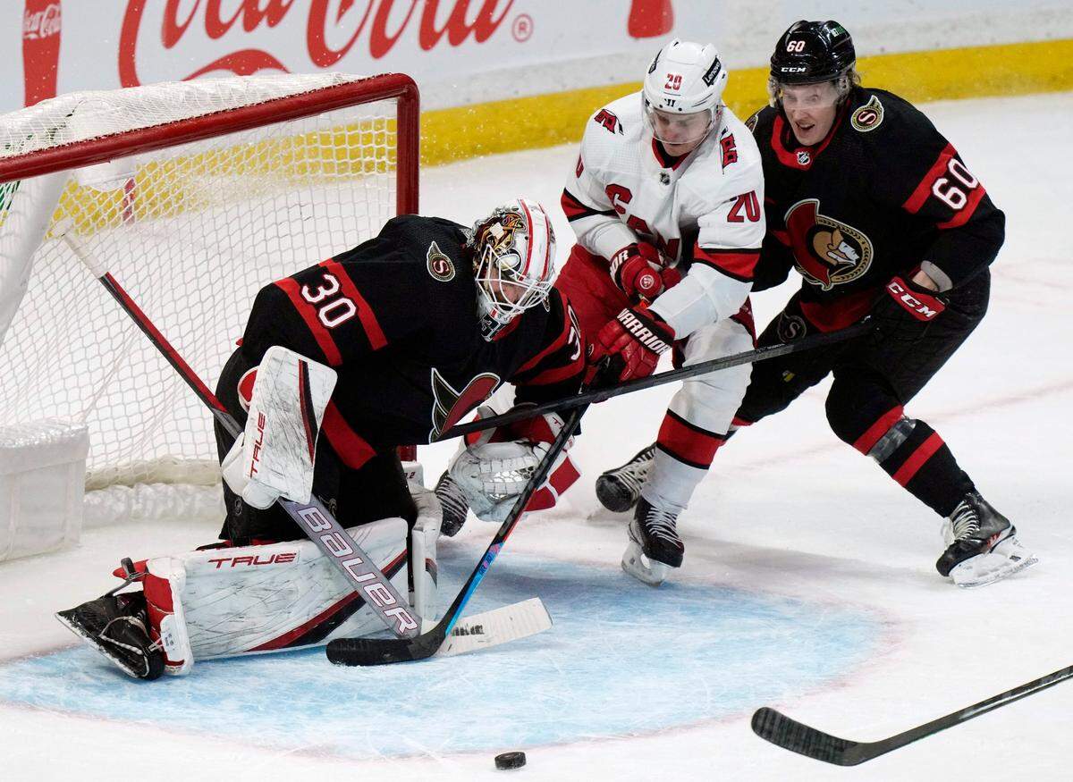 Carolina Hurricanes center Sebastian Aho loses control of the puck in front of Ottawa Senators goaltender Matt Murray as Senators defenseman Lassi Thomson defends during the second period of an NHL hockey game, Thursday, Jan. 27, 2022 in Ottawa, Ontario. (Adrian Wyld/The Canadian Press via AP)
