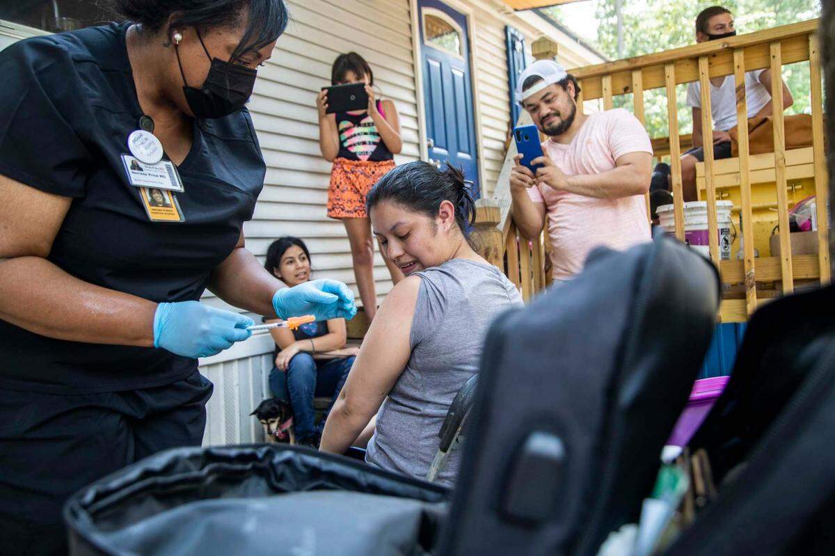 Dr. Nerissa Price administers a COVID-19 vaccine to Yeni Umanzor, 21, as volunteer canvassers went door to door offering vaccines at a Raleigh mobile home park in Raleigh on July 23.