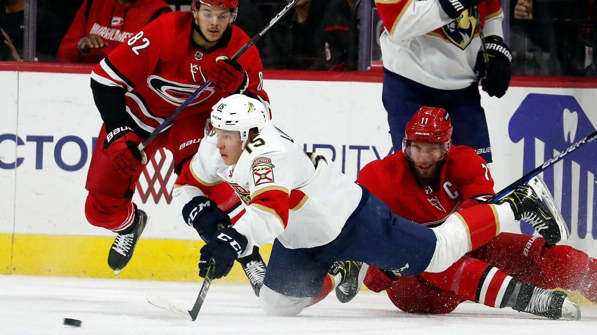 Florida Panthers’ Anton Lundell (15) trips over Carolina Hurricanes’ Jordan Staal (11) in front of Hurricanes’ Jesperi Kotkaniemi (82) during the first period of an NHL hockey game in Raleigh, N.C., Saturday, Jan. 8, 2022. (AP Photo/Karl B DeBlaker)