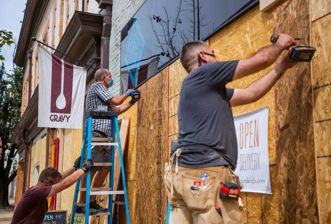 David McDonald, center, secures plywood to the windows of Sitti ahead of a planned protest against the shooting of Jacob Blake in the back this week by a police officer in Kenosha, Wisc., which has left him paralyzed, on Friday, Aug. 28, 2020, in Raleigh, N.C.
