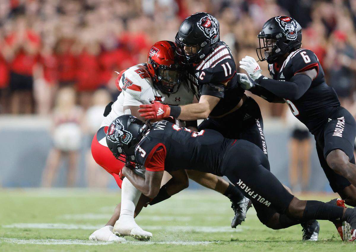 N.C. State’s Aydan White (3) and Payton Wilson (11) stop Texas Tech running back Tahj Brooks (28) during the second half of N.C. State’s 27-14 victory over Texas Tech at Carter-Finley Stadium in Raleigh, N.C., Saturday, Sept. 17, 2022. N.C. State safety Jakeen Harris (6) comes in from right.