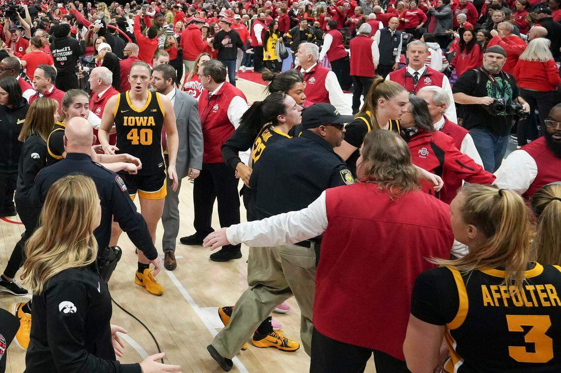Iowa guard Caitlin Clark (22) is helped off by security as fans storm the court following Ohio State’s defeat of the Hawkeyes at Value City Arena.