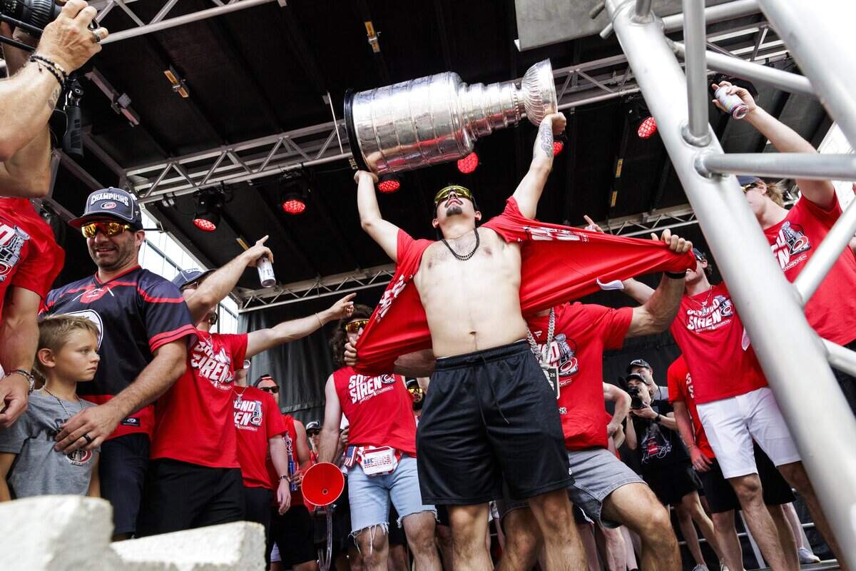 Carolina's Seth Jarvis (24) has his shirt ripped off by his teammates as he lifts the Stanley Cup during a rally on Saturday, June 20, 2026, in downtown Raleigh.