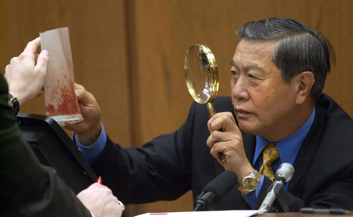 Henry C. Lee, prominent forensics expert, takes a closer look at a blood spatter evidence photo during the prosecution’s cross-examination of Lee as to his interpretation of the evidence during the 2003 Michael Peterson murder trial.