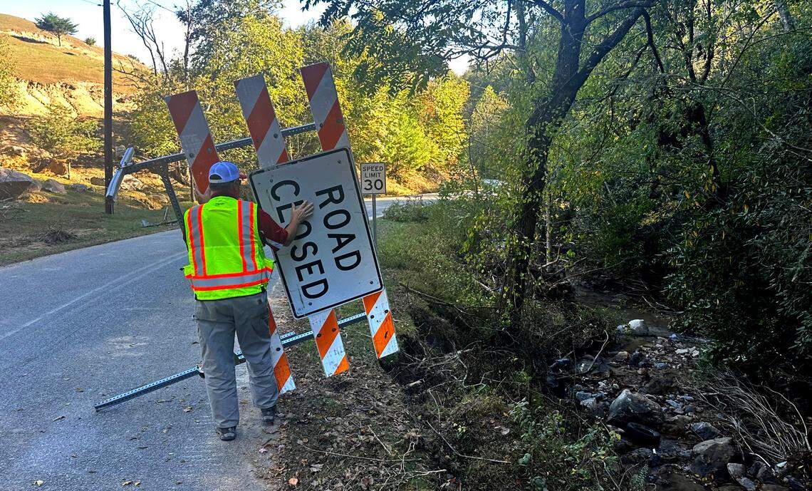 N.C. Department of Transportation engineer Battle Whitley picks up a fallen sign on Big Hungry Road in Henderson County, N.C., on Wednesday, Oct. 9, 2024. Whitley brought 21 other NCDOT workers from the Wilmington area to the mountains to help clean up after Hurricane Helene.