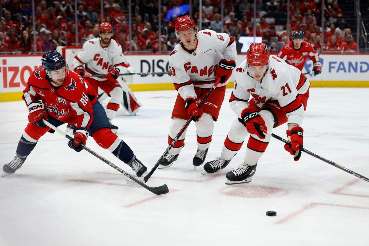 Washington Capitals left wing Andrew Mangiapane (88) battles for the puck with Carolina Hurricanes right wing Jackson Blake (53) and Hurricanes defenseman Alexander Nikishin (21) in the first period in game five of the second round of the 2025 Stanley Cup Playoffs at Capital One Arena.