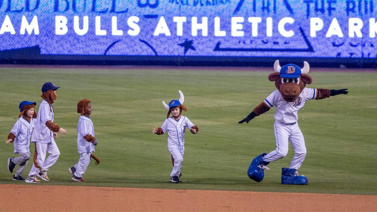 “Wool E. Bull” leads a group of children through the outfield between innings of the Durham Bulls season opener against the Norfolk Tides, Friday March 31, 2023 at the Durham Bulls Athletic Park.