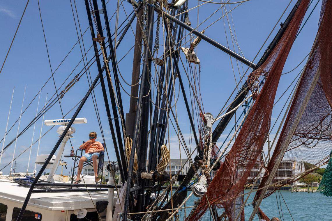 Cameron Smith, 12, relaxed on his father’s shrimp boat, the Della John, watching Beaufort Inlet Seafood workers unload the 3,100 pounds of shrimp he helped catch.
