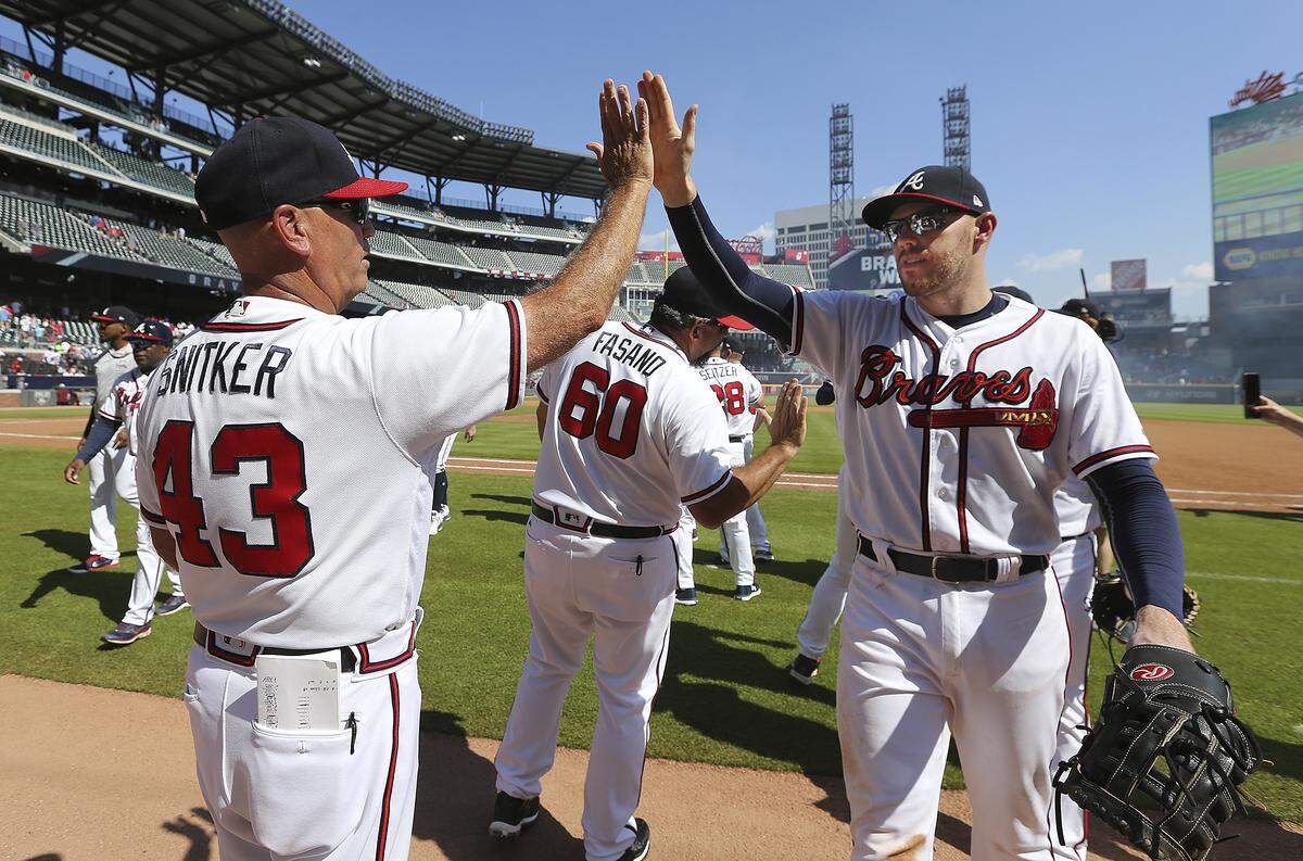 Atlanta Braves Freddie Freeman, right, who went three for three, gets a high five from manager Brian Snitker after the Braves 7-3 win over the St. Louis Cardinals on Sept. 19, 2018, in Atlanta.