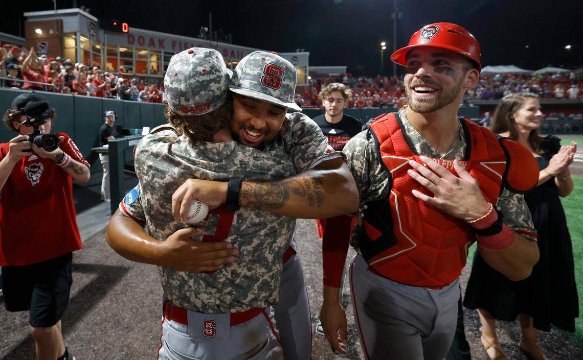 N.C. State’s Derrick Smith (25) hugs Brandon Butterworth (3) after N.C. State’s 5-3 victory over James Madison in the NCAA Raleigh Regional final at Doak Field Sunday, June 2, 2024. N.C. State’s Jacob Cozart (14) is to the right.
