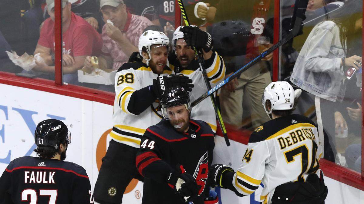 Boston’s Brad Marchand (63) celebrates with David Pastrnak (88) as Carolina’s Calvin de Haan (44) skates away after Pastrnak scored during the second period of the Carolina Hurricanes’ game against the Boston Bruins in game four of the Eastern Conference finals at PNC Arena in Raleigh, N.C. Thursday, May 16, 2019. Boston’s Jake DeBrusk (74) skates in.
