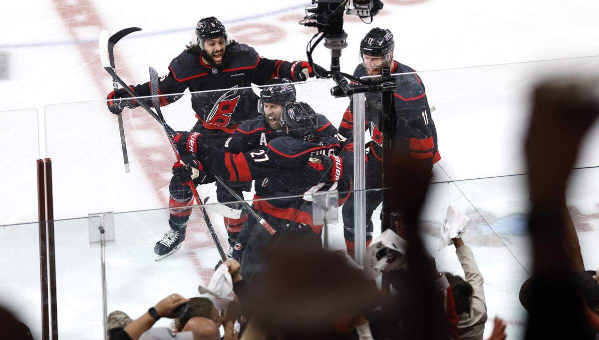 Carolina's Jalen Chatfield (5), Nikolaj Ehlers (27) and Jordan Staal (11) celebrate with Nikolaj Ehlers (27) after he made the winning shot in overtime of the Hurricanes’ 3-2 overtime victory over the Canadiens in game two of the Eastern Conference Finals at the Lenovo Center in Raleigh, N.C., Saturday, May 23, 2026.