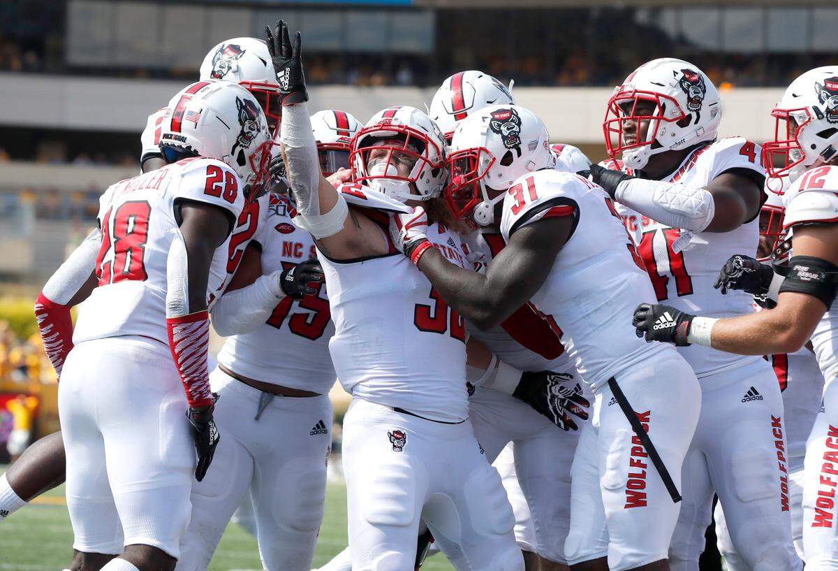 Teammates celebrate with N.C. State linebacker Drake Thomas (32) after he intercepted a pass during the second half of West Virginia’s 44-27 victory over N.C. State at Milan Puskar Stadium in Morgantown, W.V., Saturday, Sept. 14, 2019.