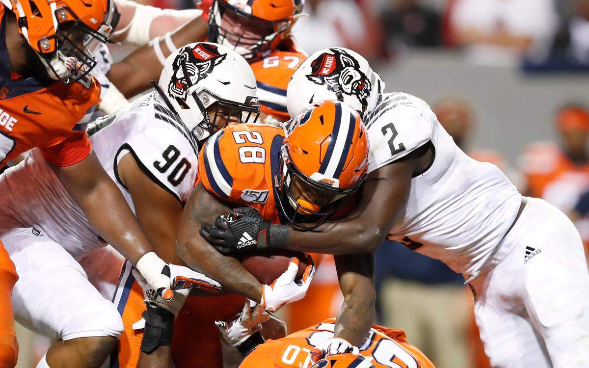N.C. State’s Savion Jackson (90) and Louis Acceus (2) tackle Syracuse running back Jarveon Howard (28) during the second half of N.C. State’s 16-10 victory over Syracuse at Carter-Finley Stadium in Raleigh, N.C., Thursday, Oct. 10, 2019.