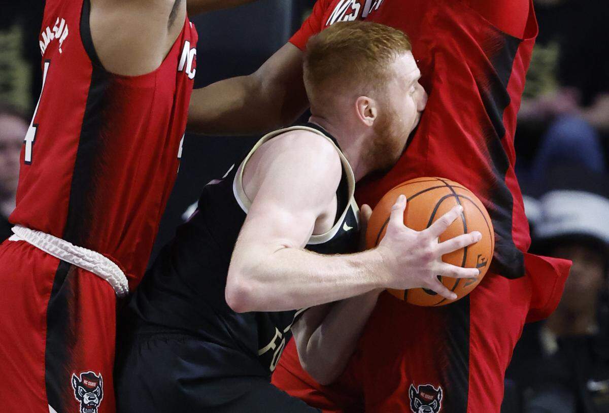 N.C. State’s LJ Thomas (4), left, and D.J. Burns Jr. (30) defend Wake Forest’s Cameron Hildreth (2) during the first half of N.C. State’s game against Wake Forest at Joel Coliseum in Winston-Salem, N.C., Saturday, Jan. 28, 2023.