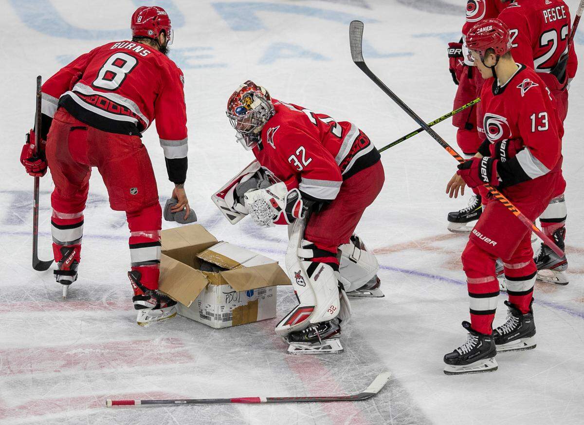 Carolina Hurricanes’ Brent Burns (8) and goalie Antii Raanta (32) grab t-shirts to toss out to fans following their 4-1 victory over Detroit on Tuesday, April 11, 2023 at PNC Arena in Raleigh, N.C.