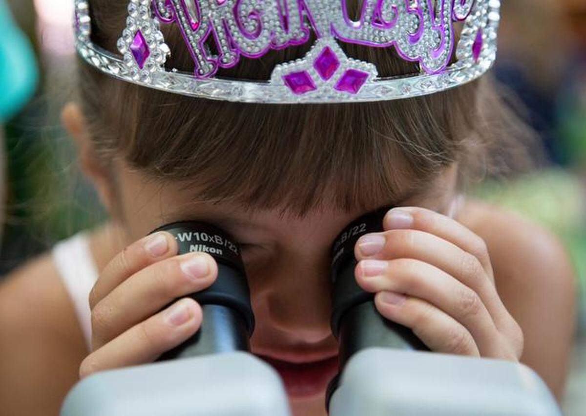 A child looks through a microscope Marbles Kids Museum at Raleigh.