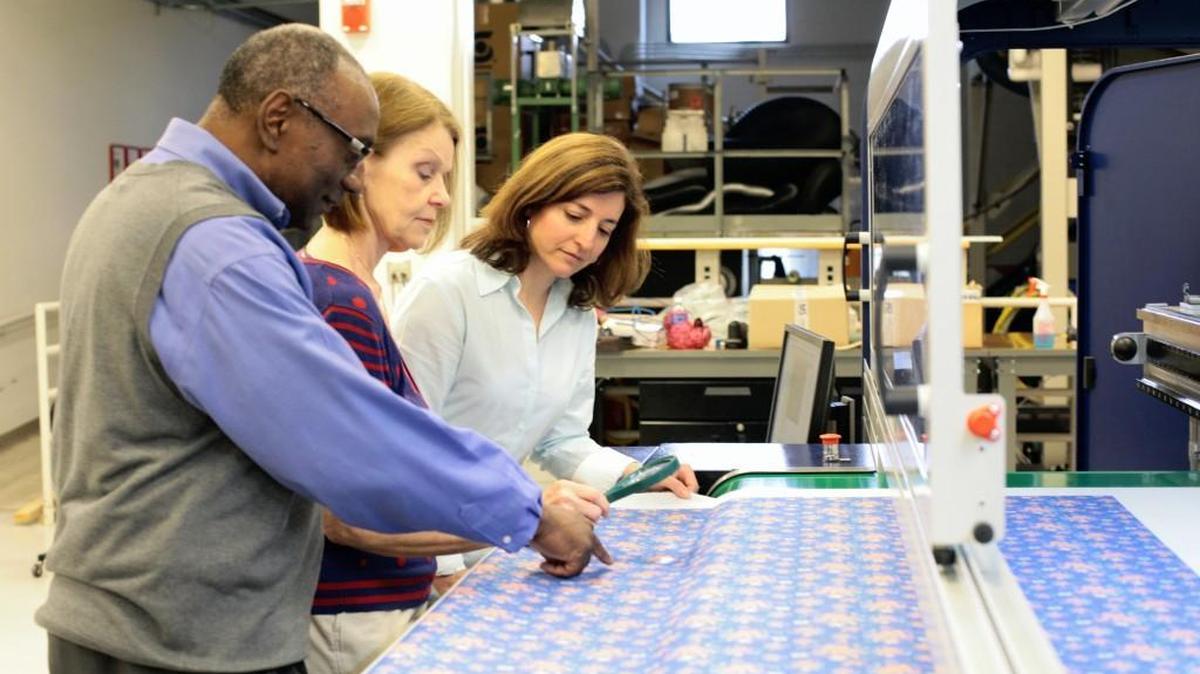 Faculty at N.C. State’s College of Textiles look at fabric printed through digital textile printing capability.