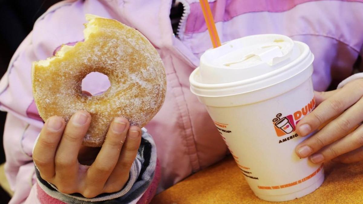 In this Feb. 14, 2013 file photo, a girl holds a beverage, served in a foam cup, and a donut at a Dunkin' Donuts in New York. The New York City Council's sanitation committee has a hearing set for Monday, Nov. 25, 2013, on proposals to ban plastic-foam food containers or explore recycling them. (AP Photo/Mark Lennihan, File)