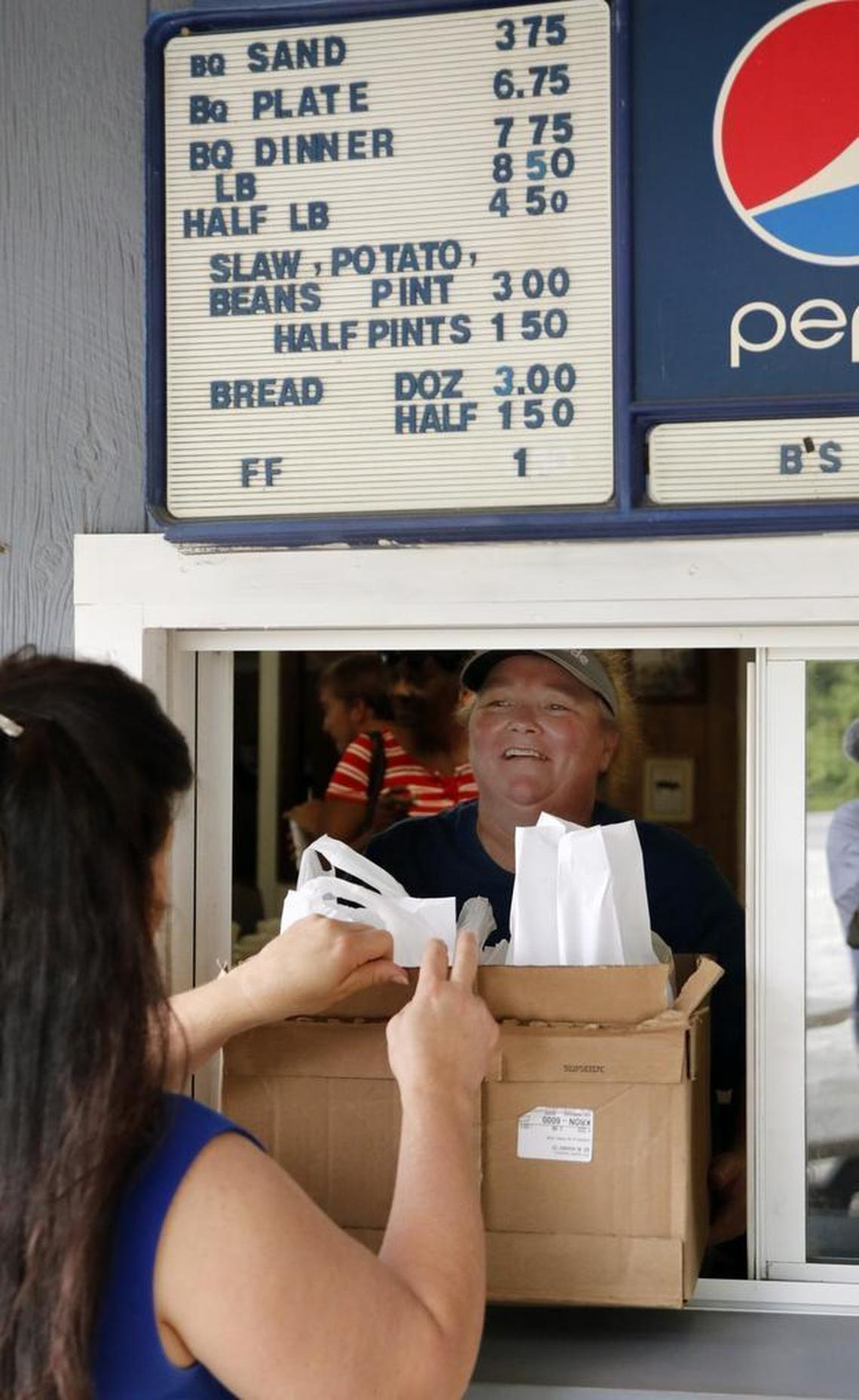 Owner Tammy Godley flashes a big smile to a customer as she hands her the order at the take-out window at B's Barbecue in Greenville NC, on June 7, 2017. B's is an old-time barbecue restaurant that ranks near the best in the state in several surveys.