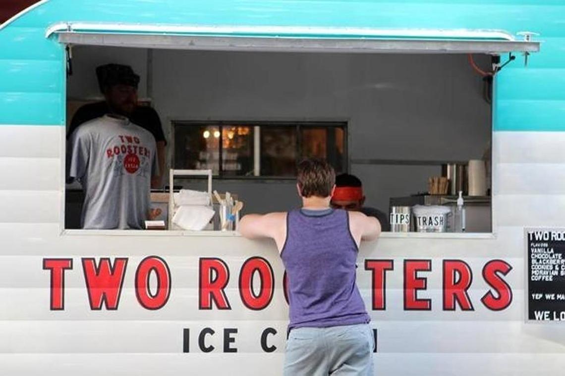 A customer buys ice cream from Two Roosters Ice Cream during a concert in downtown Raleigh on July 21, 2016. Two Roosters is bringing its vintage camper attached to a truck to Sugar Rush, an all dessert food truck rodeo.