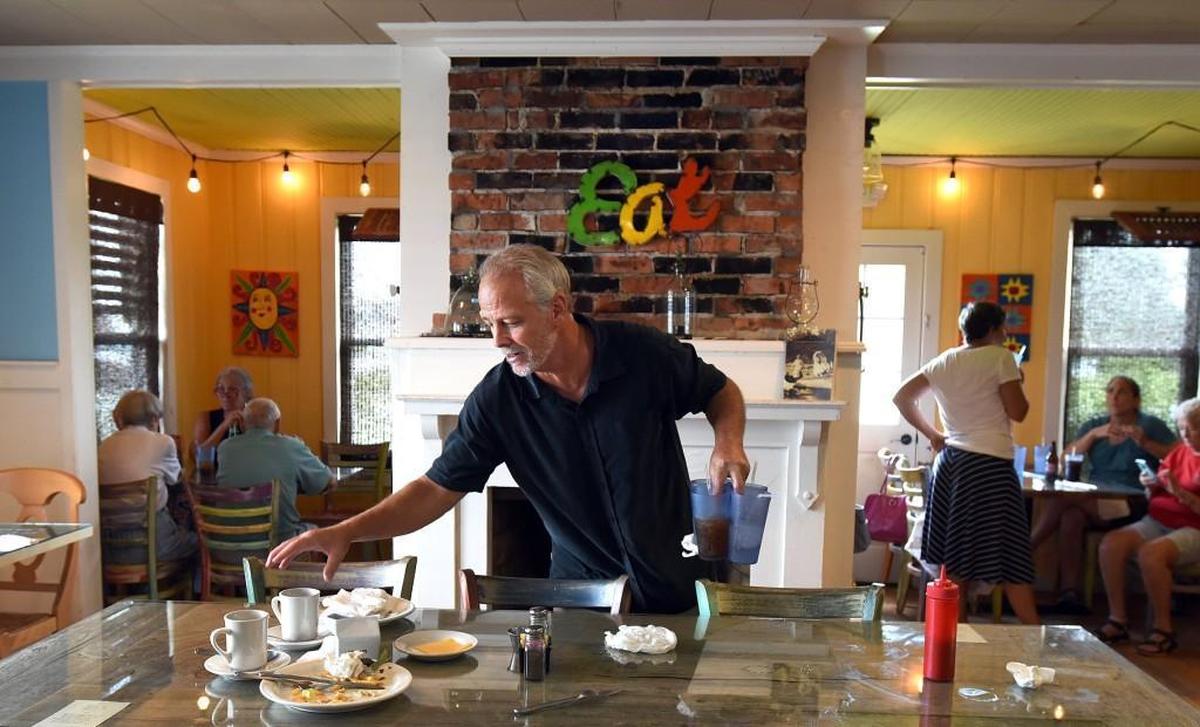 Pass the Salt Cafe owner Dan Pennington cleans up a table after diners left from lunch in Currituck, N.C., Saturday, Aug. 5, 2017. Pennington turned this rental property into a 25-seat restaurant which is the definition of a “Mom and Pop” kind of place.