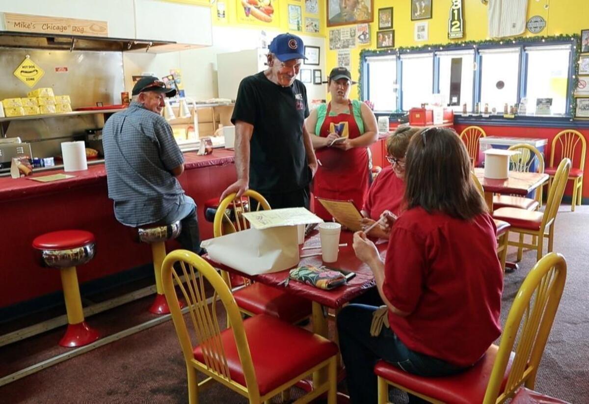 Mike's Chicago Dog (and more) in Asheboro, NC, offers authentic Chicago-style hot dogs. The walls are covered with memorabilia from Chicago sports teams. Owner Mike Jones, center, standing, with ball cap, greets customers at the restaurant on May 18, 2017.