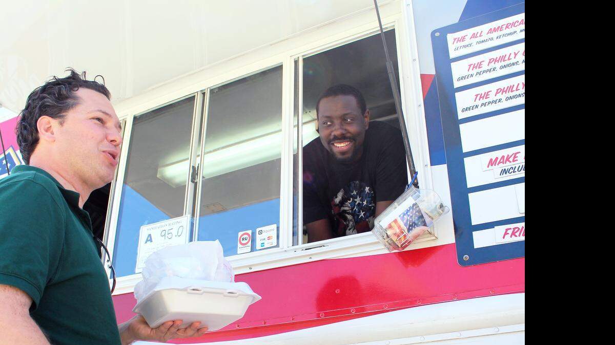 
Terrance Conway, right, leans out of All American Food Truck on April 11 to talk to Art Sheppard, a local food truck blogger. Conway started the food truck in 2014 with Bobby Fulghum of Holly Springs. When he’s not working with his truck, he’s playing with or coaching the Cary Invasion semi-pro basketball team.
