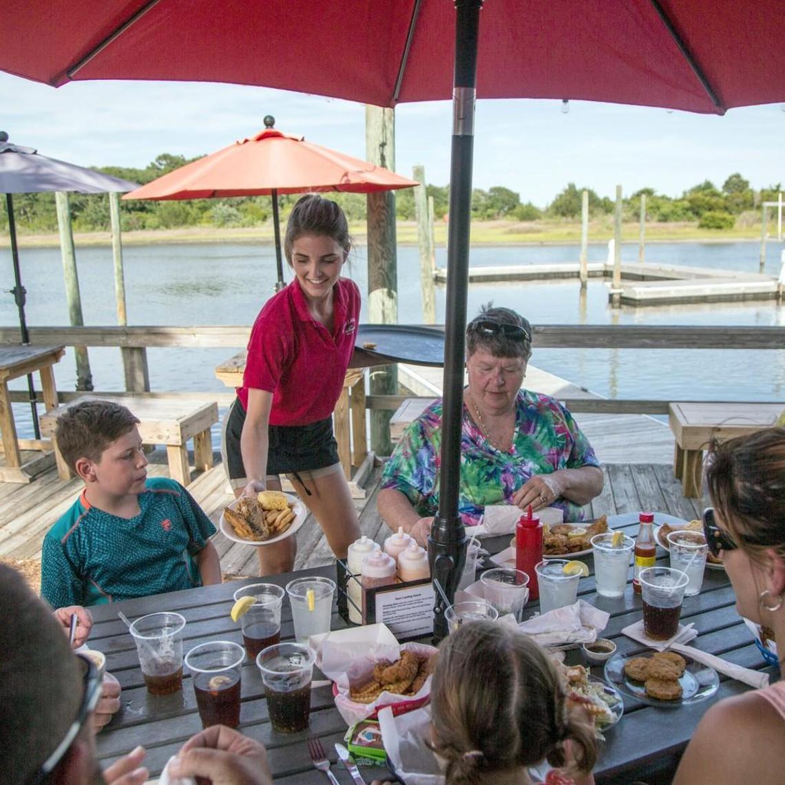 Kenzie Hansley serves a group sitting at dockside tables overlooking the Intracoastal Waterway at Sears Landing Grill & Boat in Surf City.