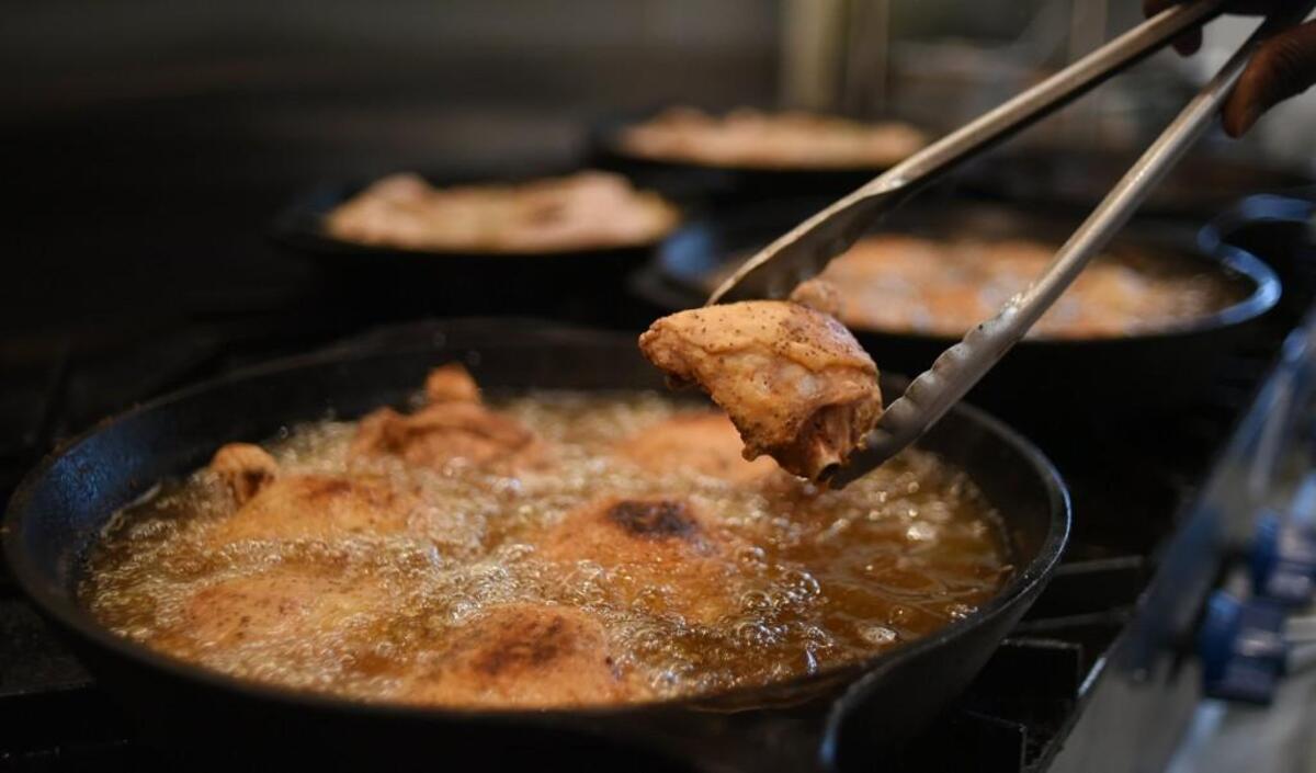 Fried chicken is pulled out of a cast iron skillet at Miss Ora’s Kitchen restaurant in Winston-Salem, N.C., Thursday, July 27, 2017. Miss Ora’s Kitchen is next door to Sweet Potatoes restaurant on North Trade Street. It opened in July 2017. The recipe comes from one of the owner’s grandmothers.