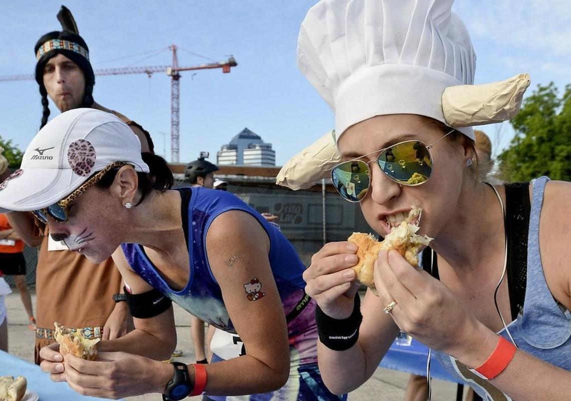 Jessi Blakely (right) and Caren Mangarwlli (left), pictured in 2015, chow down on a Bratwurst from Motorco as they start the lead-off leg of the seventh annual Doughman race in Durham.
