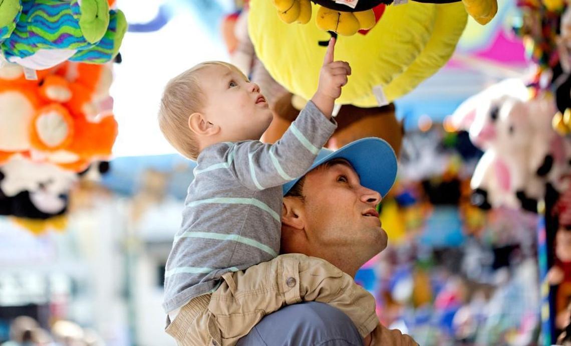Gray Shelton, 1, of Mount Ulla, N.C. reaches to touch a stuffed animal prize atop of his father Ryan Shelton's shoulders at the N.C. State Fair Friday, Oct. 14, 2016 in Raleigh, N.C.