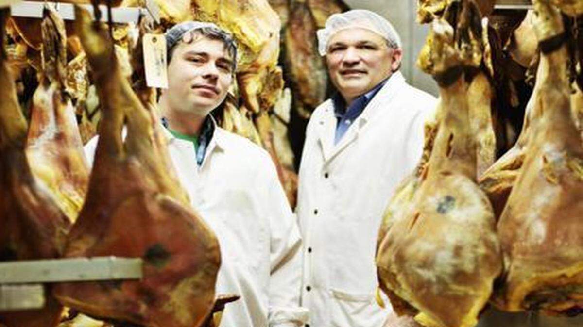 
Sam Suchoff, left, and Rufus Brown at Smithfield Country Ham in Smithfield, where Suchoff has 18,000 pounds of country ham aging inside Brown’s ham room. The hams hang from hooks above a sawdust-covered floor. 


