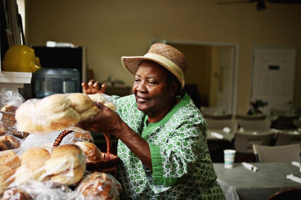 Volunteer Esther Neal sorts the donated bread on a table for people to take home after they dine at the weekly Community Lunch at St. Bartholomew’s Episcopal Church in Pittsboro on Oct. 12, 2017.