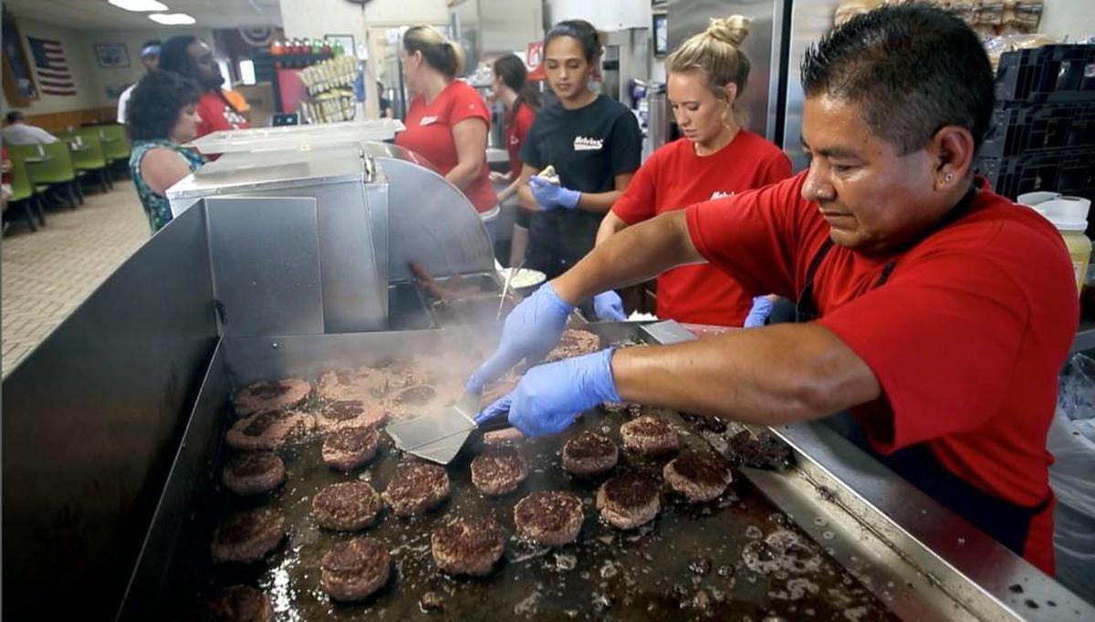 Luis Santiago mans the grill, cooking hamburgers the same way that Melvins’ has done for nearly 80 years on Friday, June 30, 2017 in Elizabethtown, N.C.