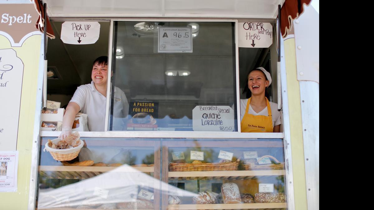
From left, Stephanie Caronna and Alexis Berlin offer bread samples to visitors at the Western Wake Farmers Market located in the UNC Wellness Center parking lot Saturday, May 2, 2015 in Cary, N.C.
