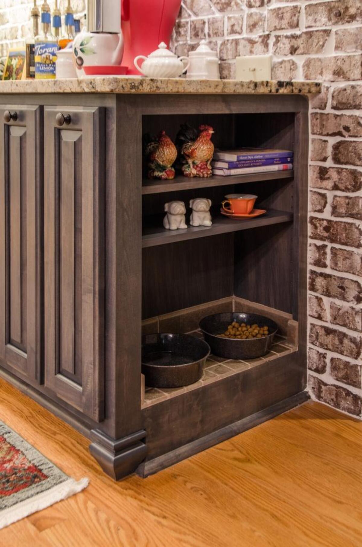For a recent kitchen remodel, reInventedSpaces LLC incorporated a dog feeding station into the side of a custom base cabinet. They added shelving and a tile base for practicality purposes.