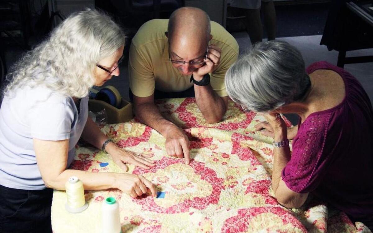 
Suzan and Mark deSerres consult with Marilyn Huntress of Southern Pines, who brought in a quilt she made for her granddaughter's wedding six years ago for repairs.
