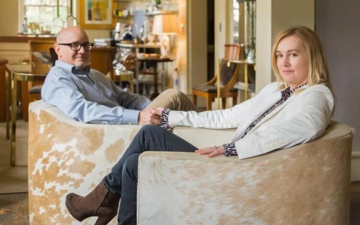 
Chris and Beth Collier sit in hide-covered swivel chairs they designed; beyond lies their open dining room and kitchen.


