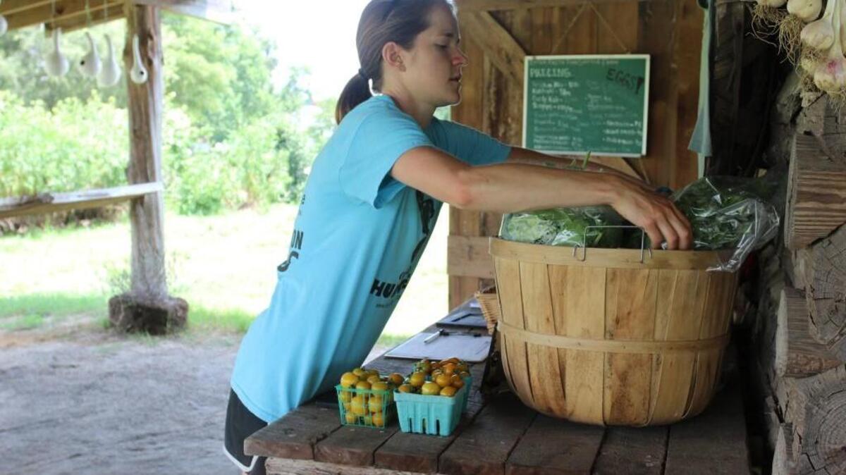 Becky Dobosy arranges produce at the Inter-Faith Food Shuttle farm stand on Dover Farm Road in Raleigh. The stand is open Fridays and Saturdays through the summer.