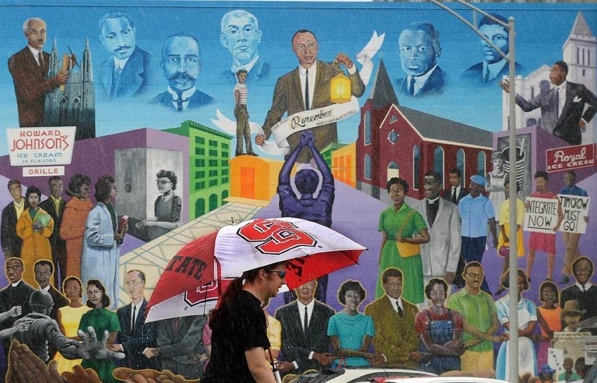 A pedestrian walks past the Durham Civil Rights History Mural project Friday, October 2, 2015. The mural covers over 2,000 square feet of wall space on the side of the Visitors and Convention Center facing Morris Street, next to Durham Arts Council.