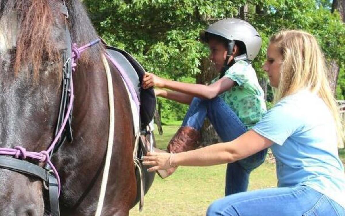 
Hilary Schofield of Hope Reins helps Keren Mestas, 10, into the saddle at Hope Reins, a nonprofit that works with children who are dealing with problems such as grief or trauma. The ranch has a new home off Route 98 near North Raleigh.
