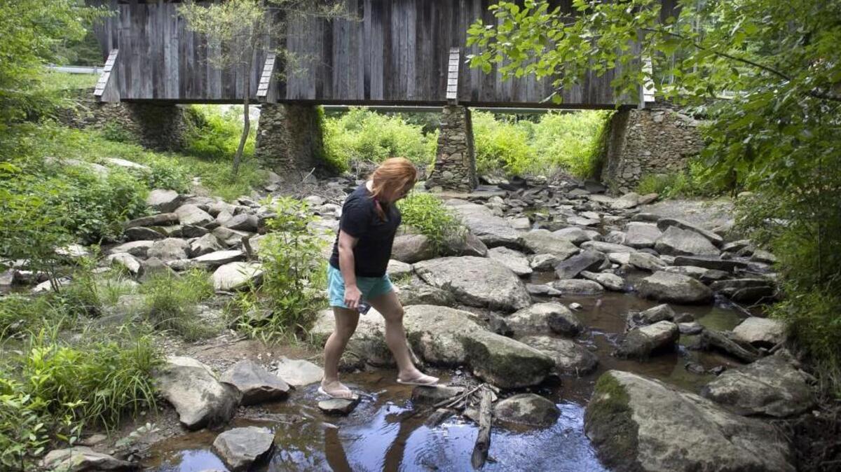 Megan Tyler of Hampstead, N.C. steps carefully across the West Fork Little River below the Pisgah Covered Bridge to make some photographs on July 11, 2015 near Asheboro, N.C. Tyler and her family visited the Pisgah Covered Bridge after a visit to the North Carolina Zoo in Asheboro.