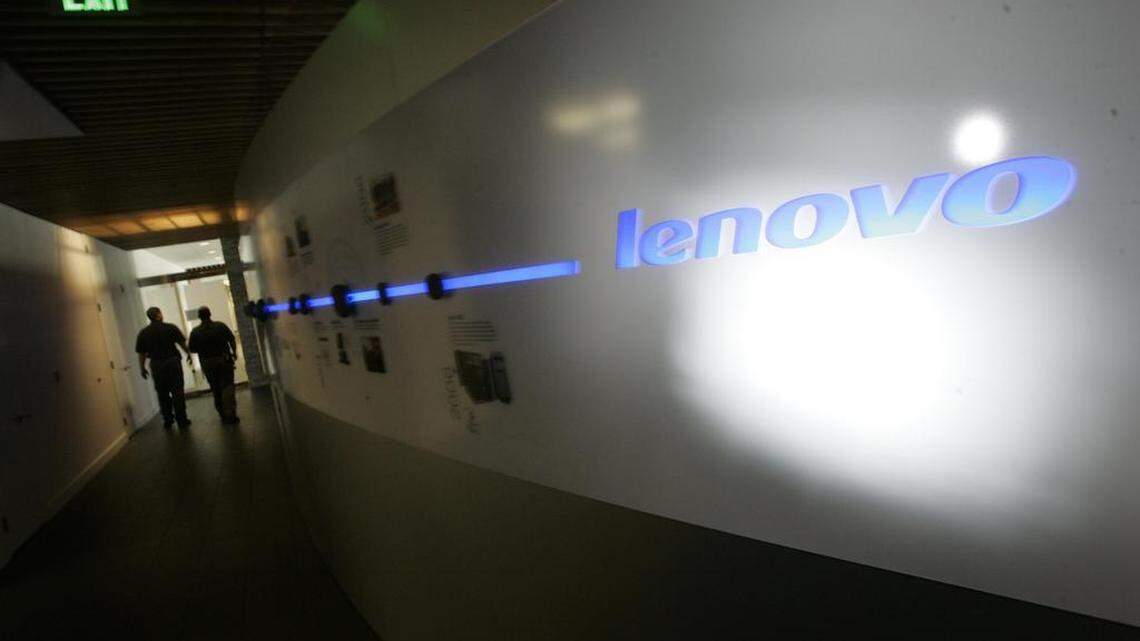 Lenovo has announced a round of job cuts. Workers walk past a Lenovo sign in this 2007 file photo.